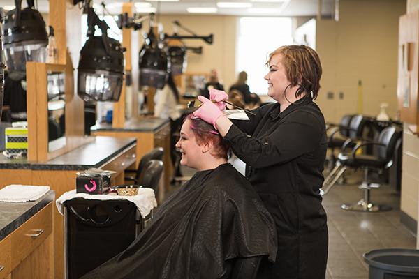 A cosmetology student practices cutting hair