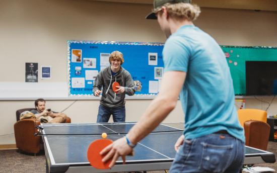 two students playing ping pong in the student commons