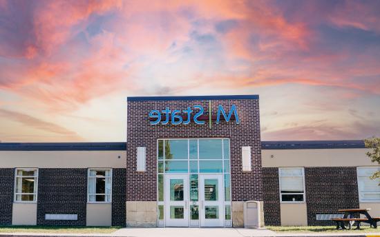 A photo of the exterior of M州-Wadena with a pink and blue sunset above the building